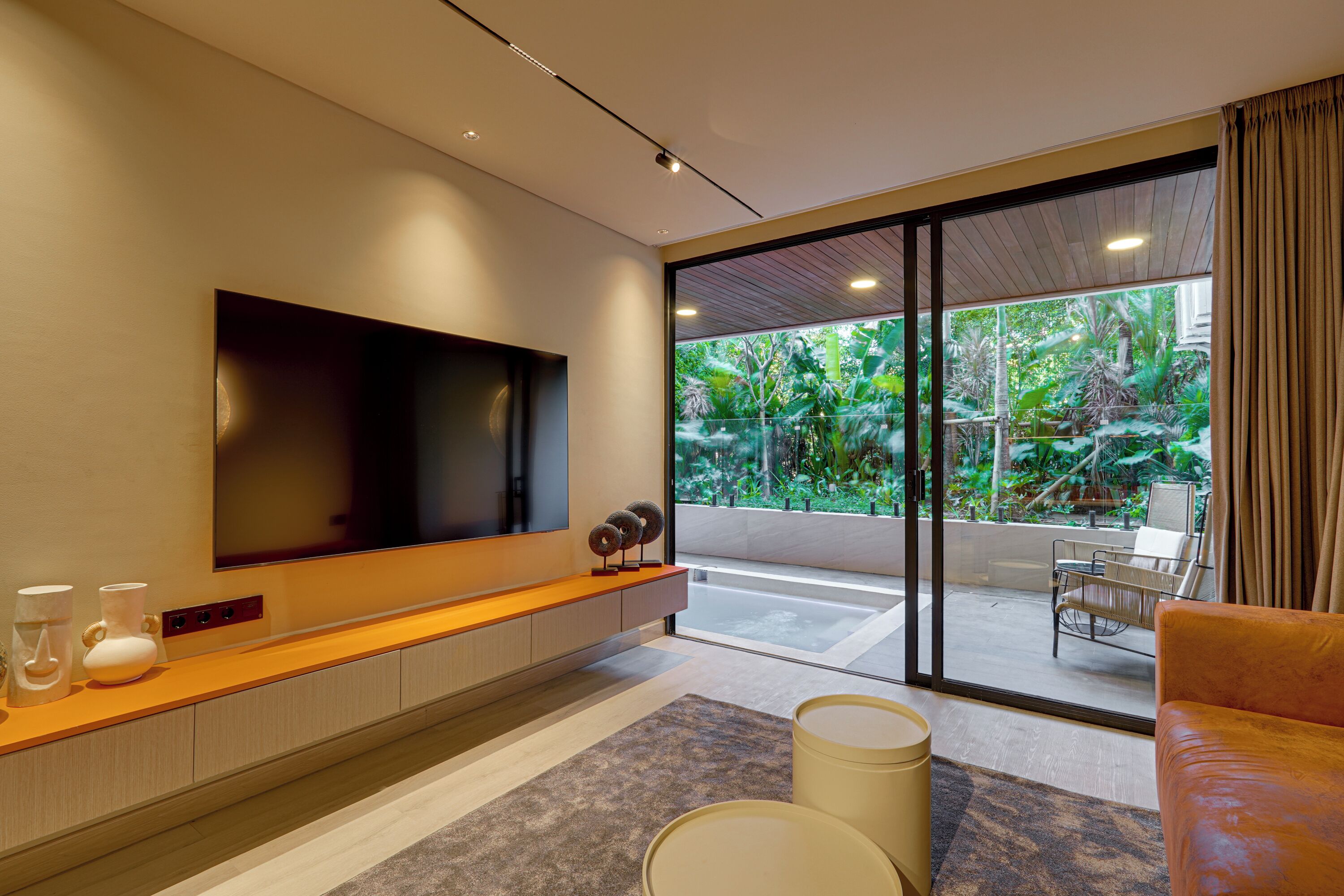 A modern living room with a large flat-screen TV, a wooden console table, and a comfortable seating area with a sofa and armchair.