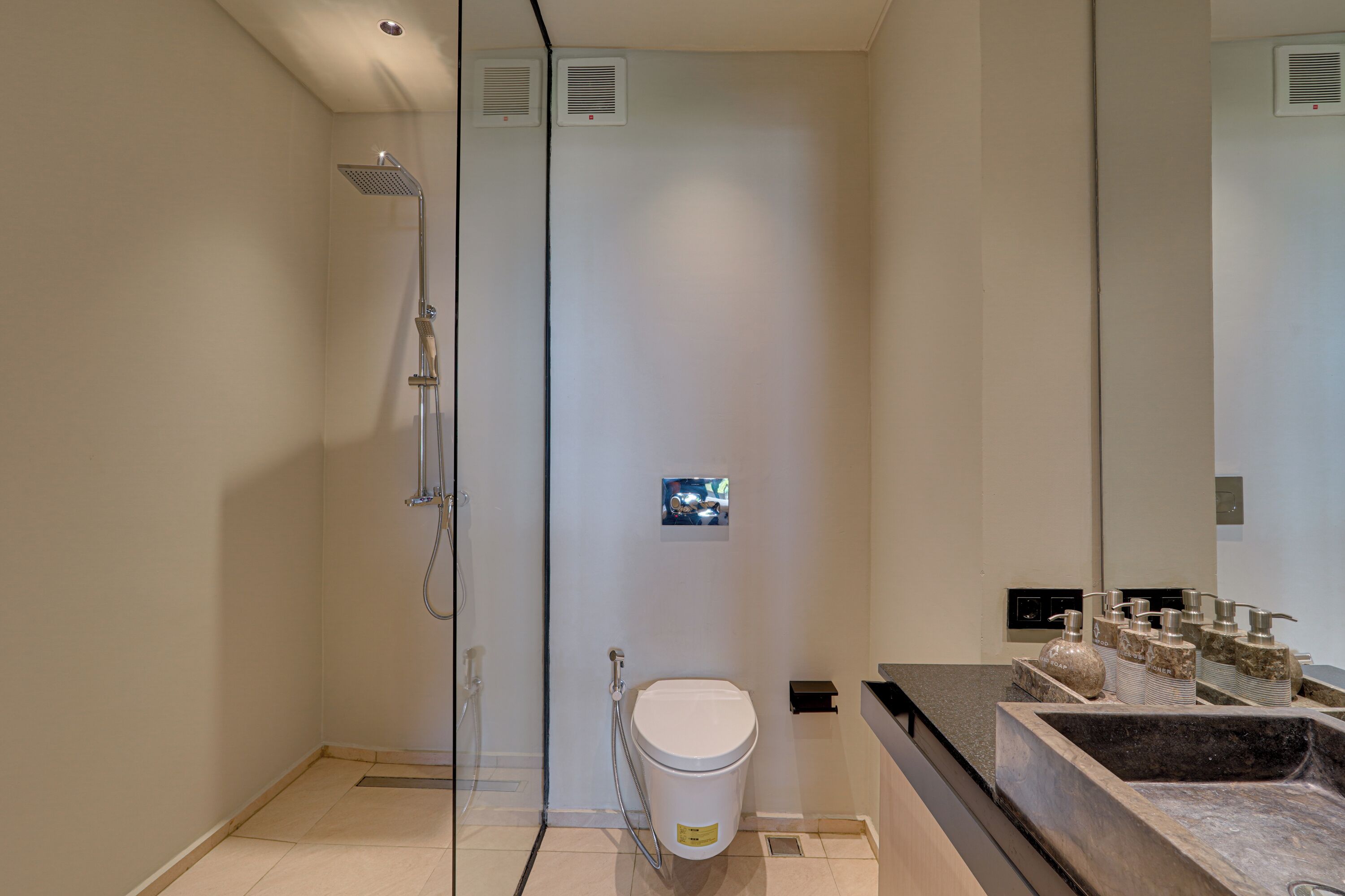 Un baño moderno con ducha de vidrio, inodoro y lavamanos de mármol.