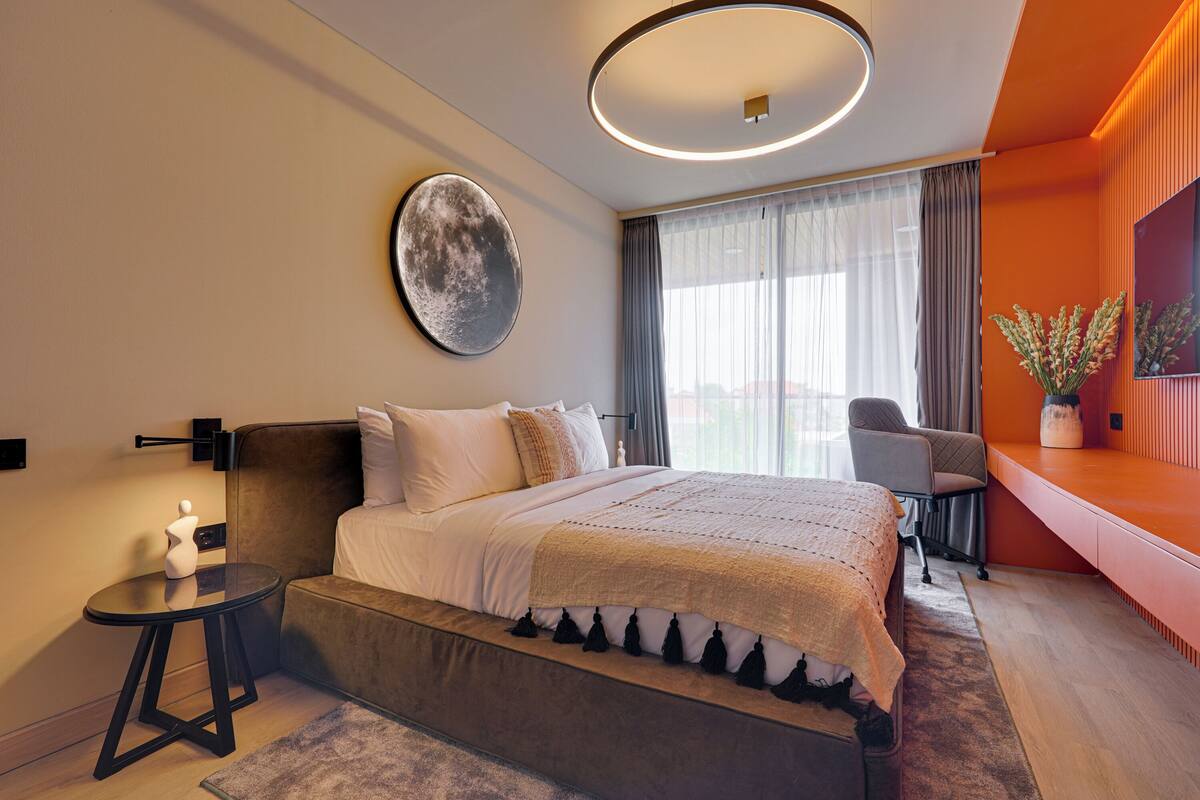 Una habitación de hotel moderna con una cama grande, un escritorio y vistas a la ciudad.