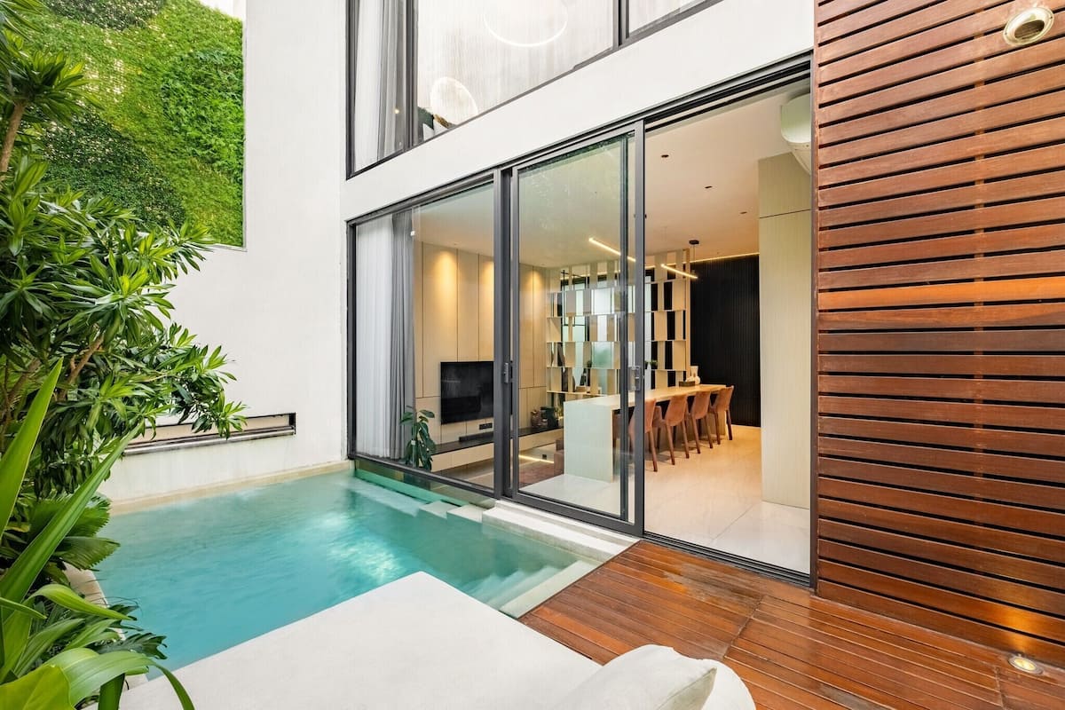 Una casa moderna con piscina, un comedor y una cocina visibles a través de puertas de vidrio.