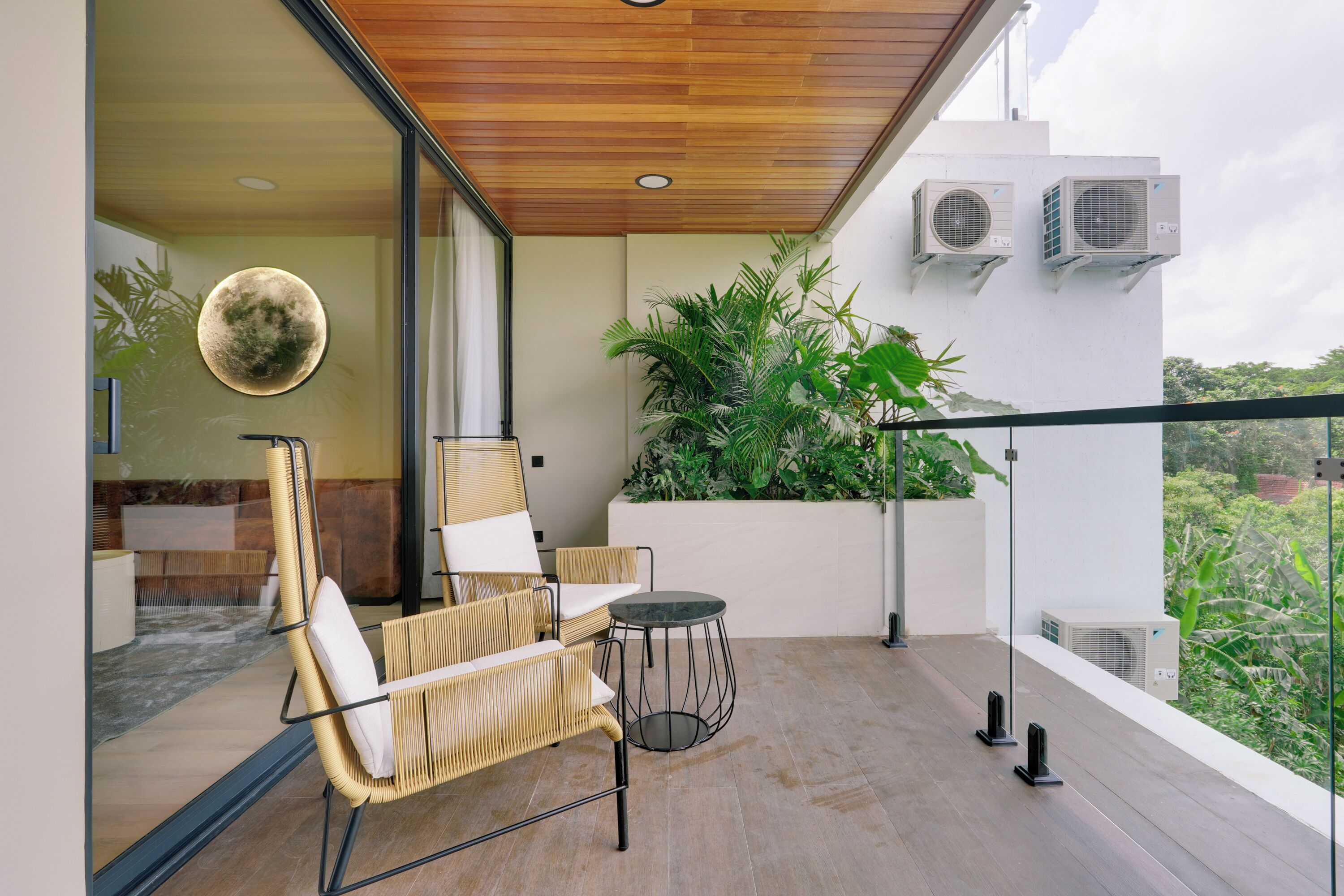 A balcony with wicker chairs, a small round table, and potted plants.