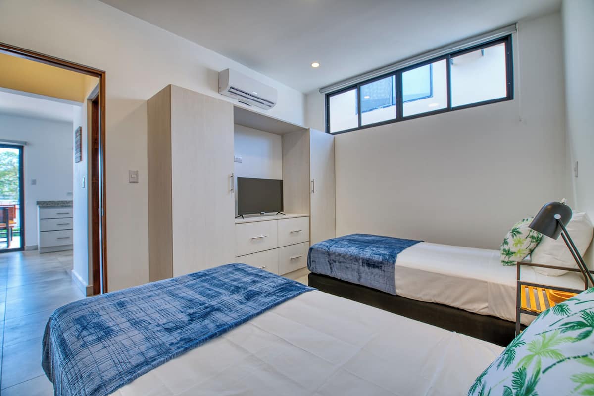 Ein modernes Schlafzimmer mit zwei Betten, einem Fernseher und einem Fenster.