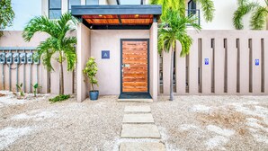 Un edificio moderno con puerta de madera, entrada cubierta y camino de acceso de grava.