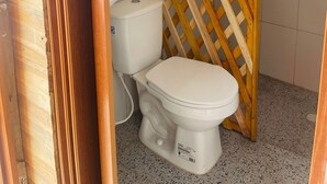 A bathroom with a wooden lattice partition, a white toilet, and a towel hanging on the wall. - Family room in a beachfront cabin - Barú (Cartagena)