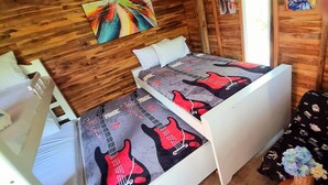 A room with a bunk bed, a wooden wall, and a colorful abstract painting. - Family room in a beachfront cabin - Barú (Cartagena)
