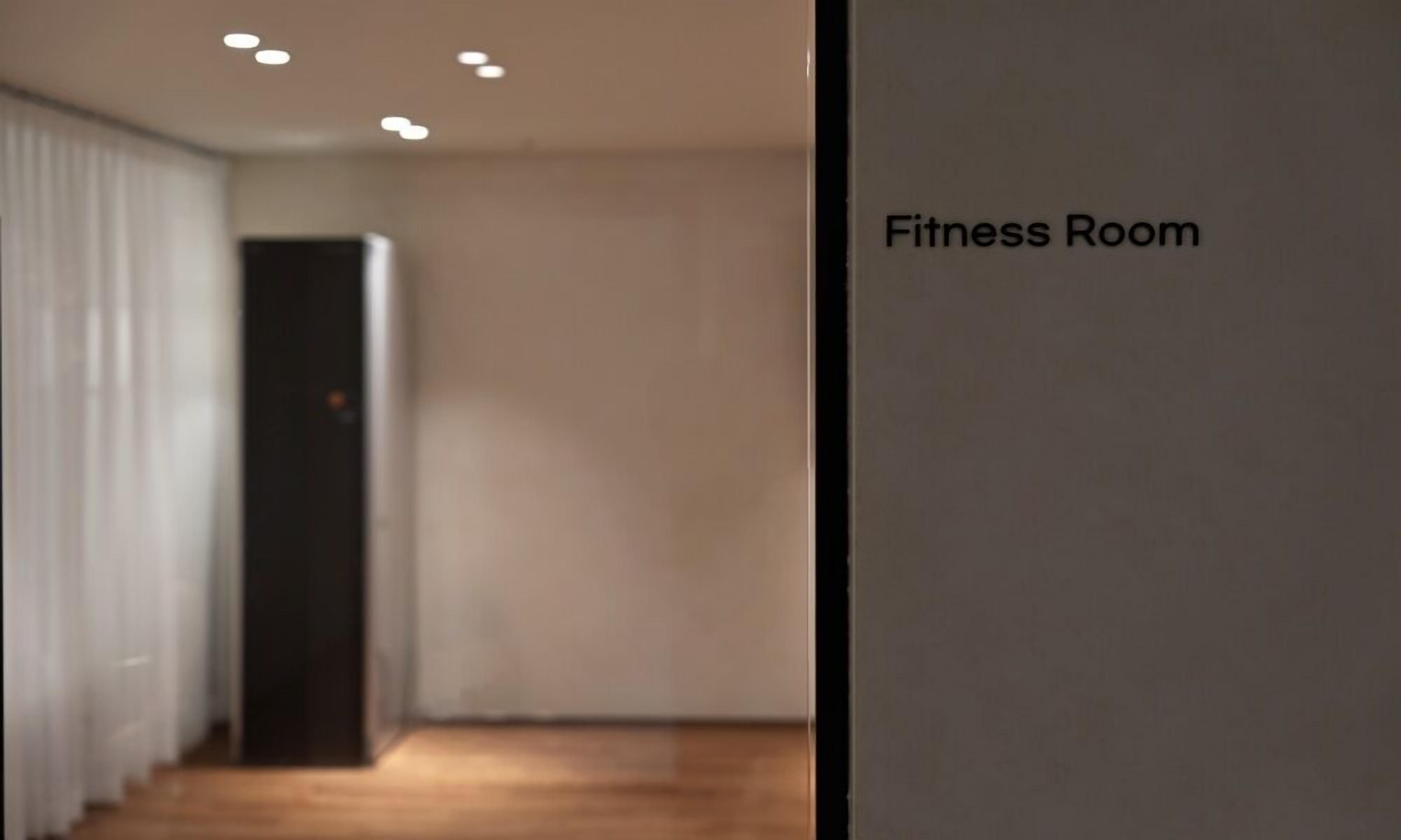 Un gimnasio con una pared lisa y una puerta que da a otra habitación.