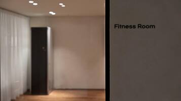 Un gimnasio con una pared lisa y una puerta que da a otra habitación.
