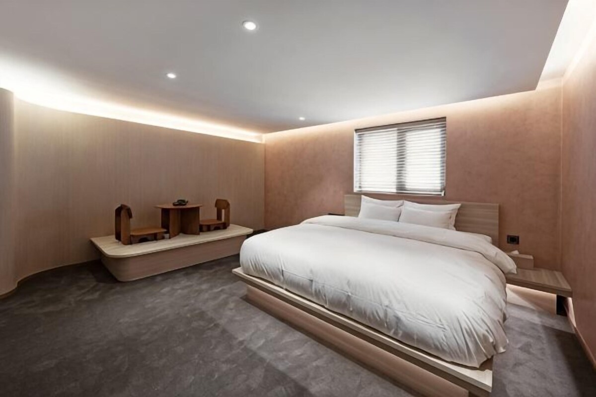 Un dormitorio con una cama grande, una mesita de noche y un banco empotrado con espacio de almacenamiento.