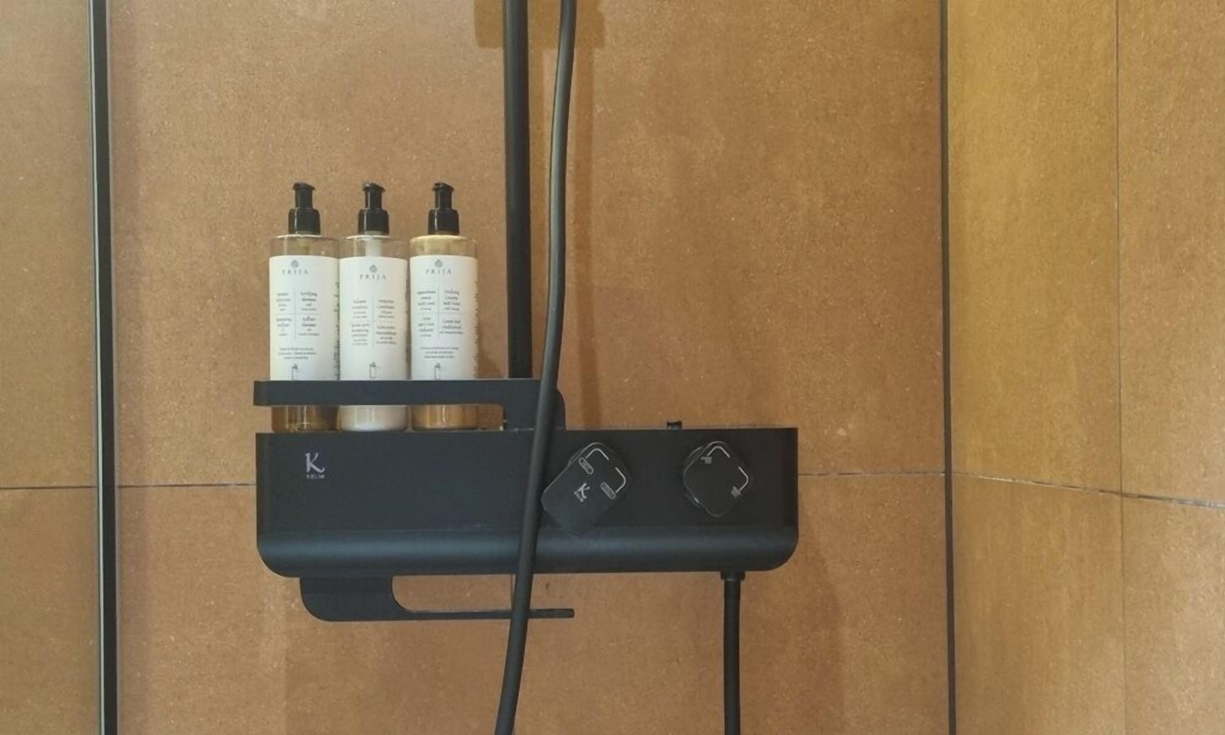 Un baño con un mueble de tocador negro que contiene tres botellas de champú y acondicionador.