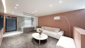 Un salon moderne avec un canapé, une table basse agrémentée d’un vase, une douche en verre et un éclairage encastré au plafond.