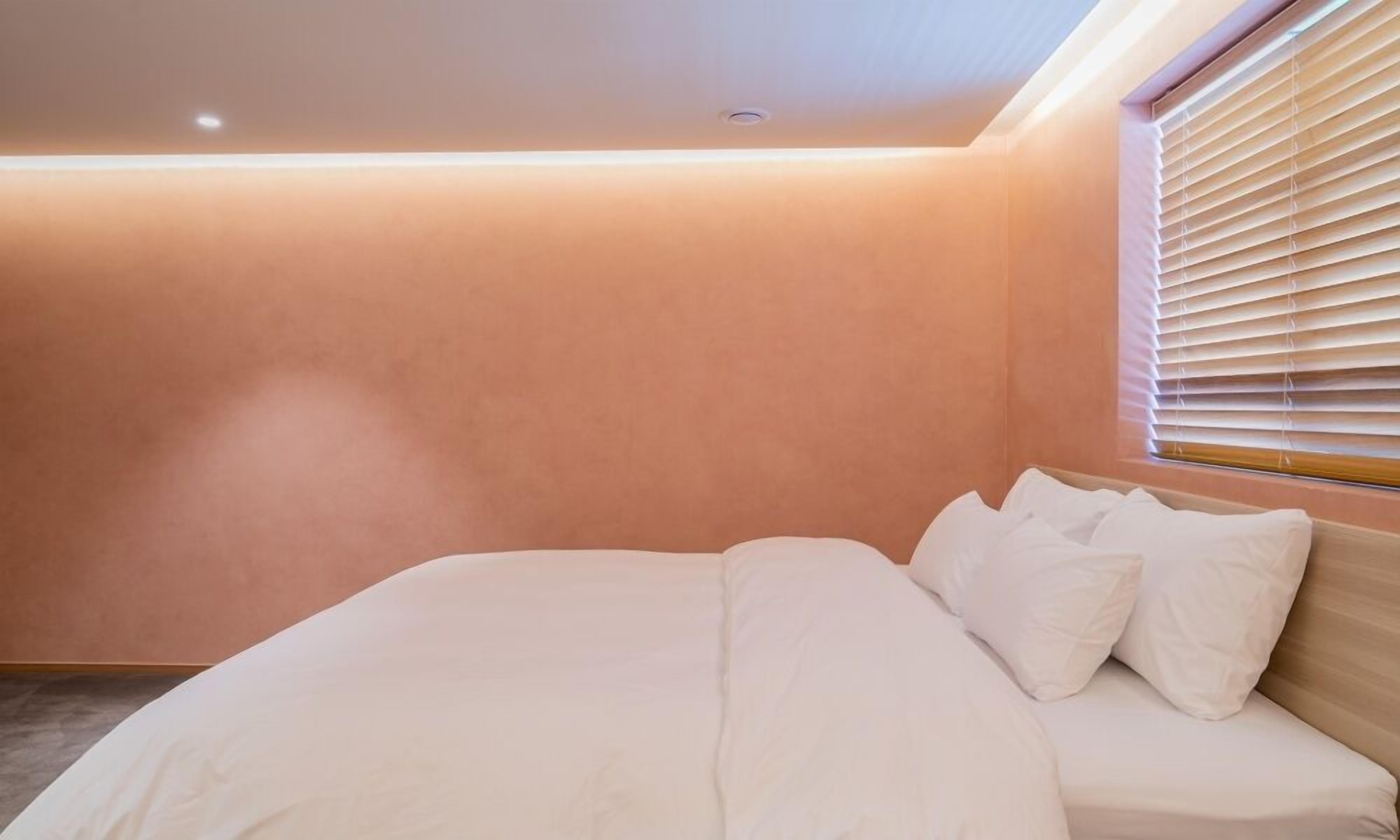 Un dormitorio con cama, ventana con persianas y luz de techo.