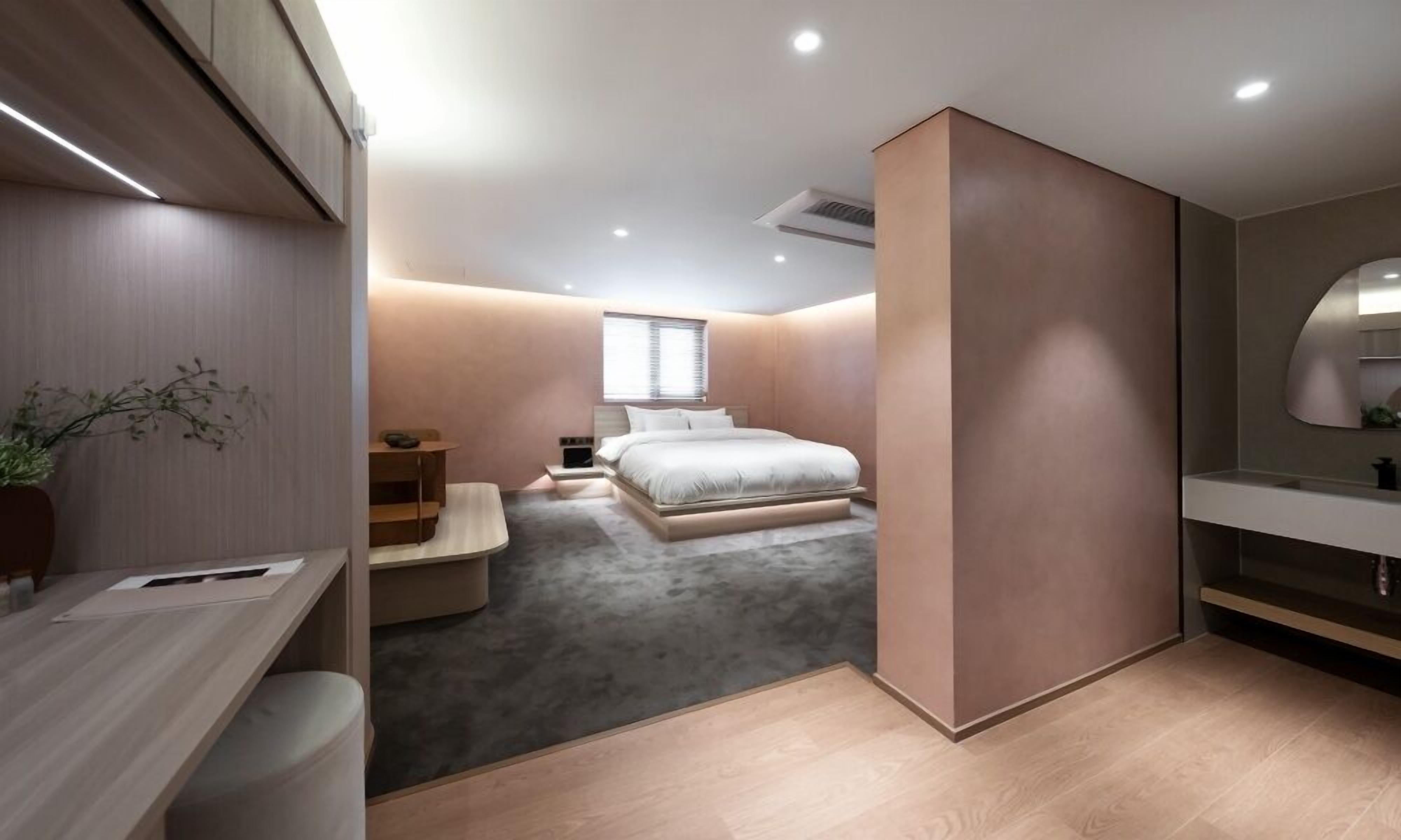 A modern bedroom with a bed, bedside tables, a desk, and a large mirror.