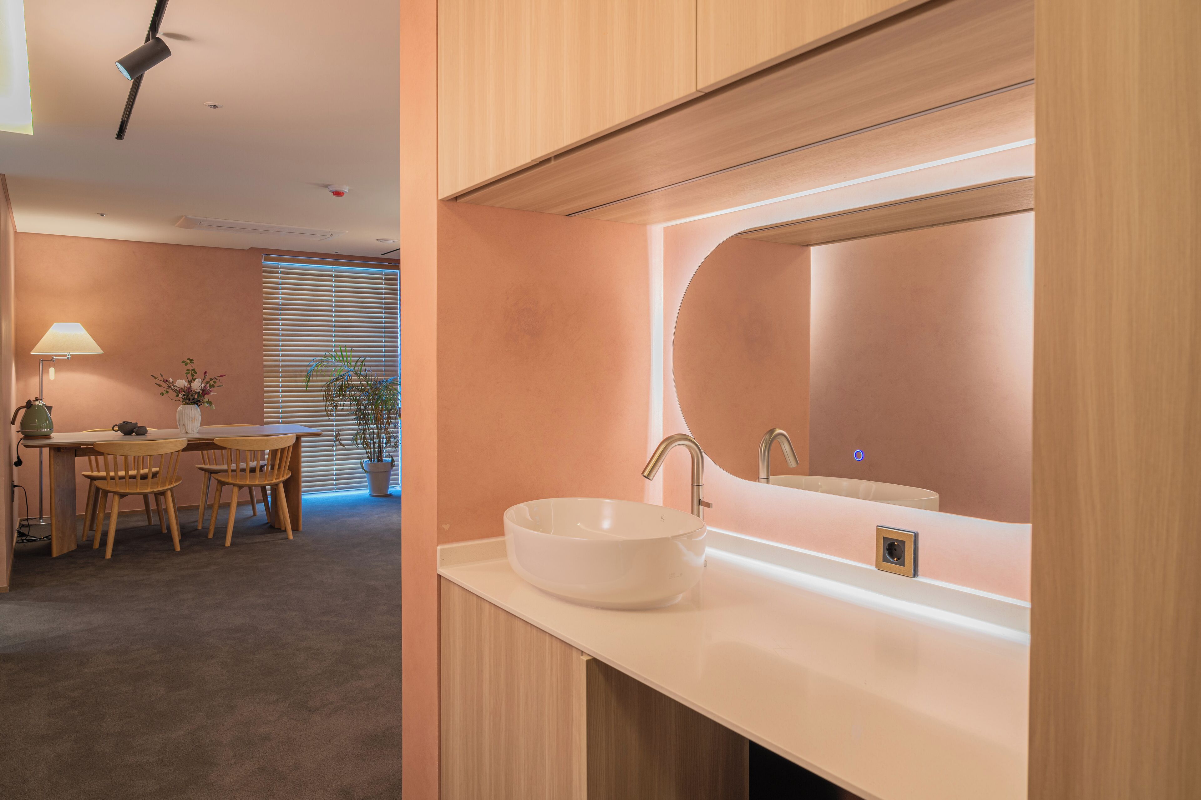 A modern bathroom with a large mirror, a white sink, and a wooden vanity.