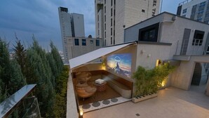 Une terrasse sur le toit, dotée d’un espace salon, d’une grande fresque murale et offrant une vue sur le paysage urbain.