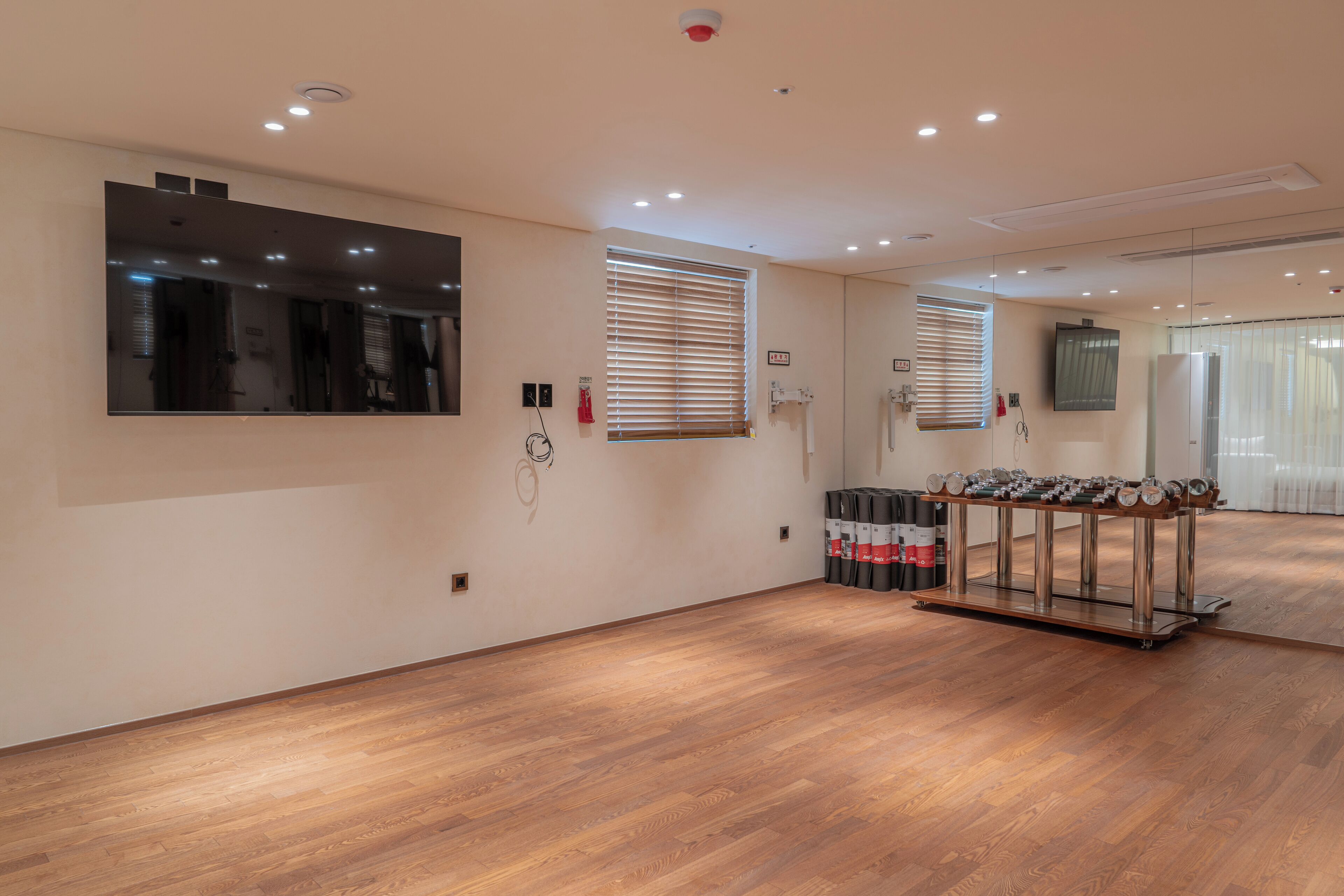 A spacious room with wooden flooring, a large mirror, and a shoe rack.