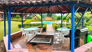 Un patio al aire libre con una parrilla, asientos y vistas a una piscina.