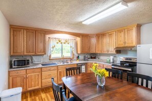 Une cuisine avec des meubles de rangement en bois, un four à micro-ondes, un évier et une table à manger avec des chaises.