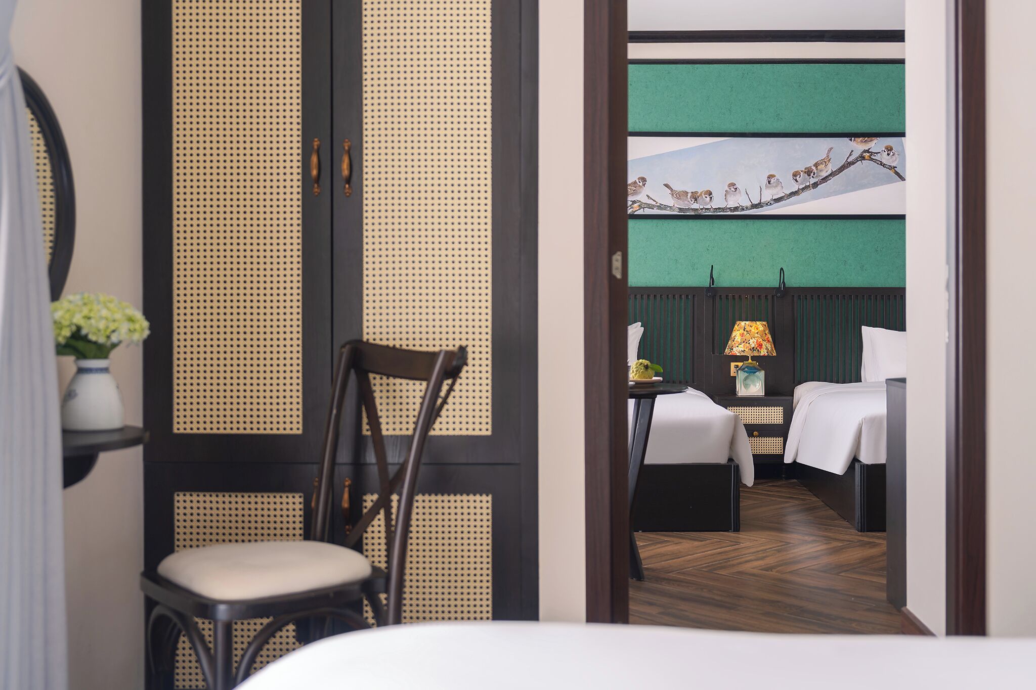 Ein Hotelzimmer im traditionellen Stil mit Tatami-Boden, einem Holzsessel, einem Bett und einem Nachttisch mit Lampe.