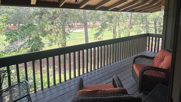 A covered porch with a view of a landscaped garden. - Golfer’s Dreamhouse (Pinehurst)