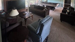 A living room with a fireplace, a pool table, and a sofa. - Golfer’s Dreamhouse (Pinehurst)
