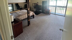 A room with a bunk bed, desk, chair, and a view through a sliding glass door. - Golfer’s Dreamhouse (Pinehurst)