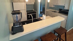 A kitchen with a central island, bar stools, a blender, and pendant lighting. - Golfer’s Dreamhouse (Pinehurst)