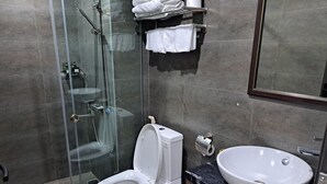 Ein modernes Badezimmer mit einer Glaskabine zur Dusche, einer weißen Toilette und einer Marmorarbeitsplatte mit Waschbecken.