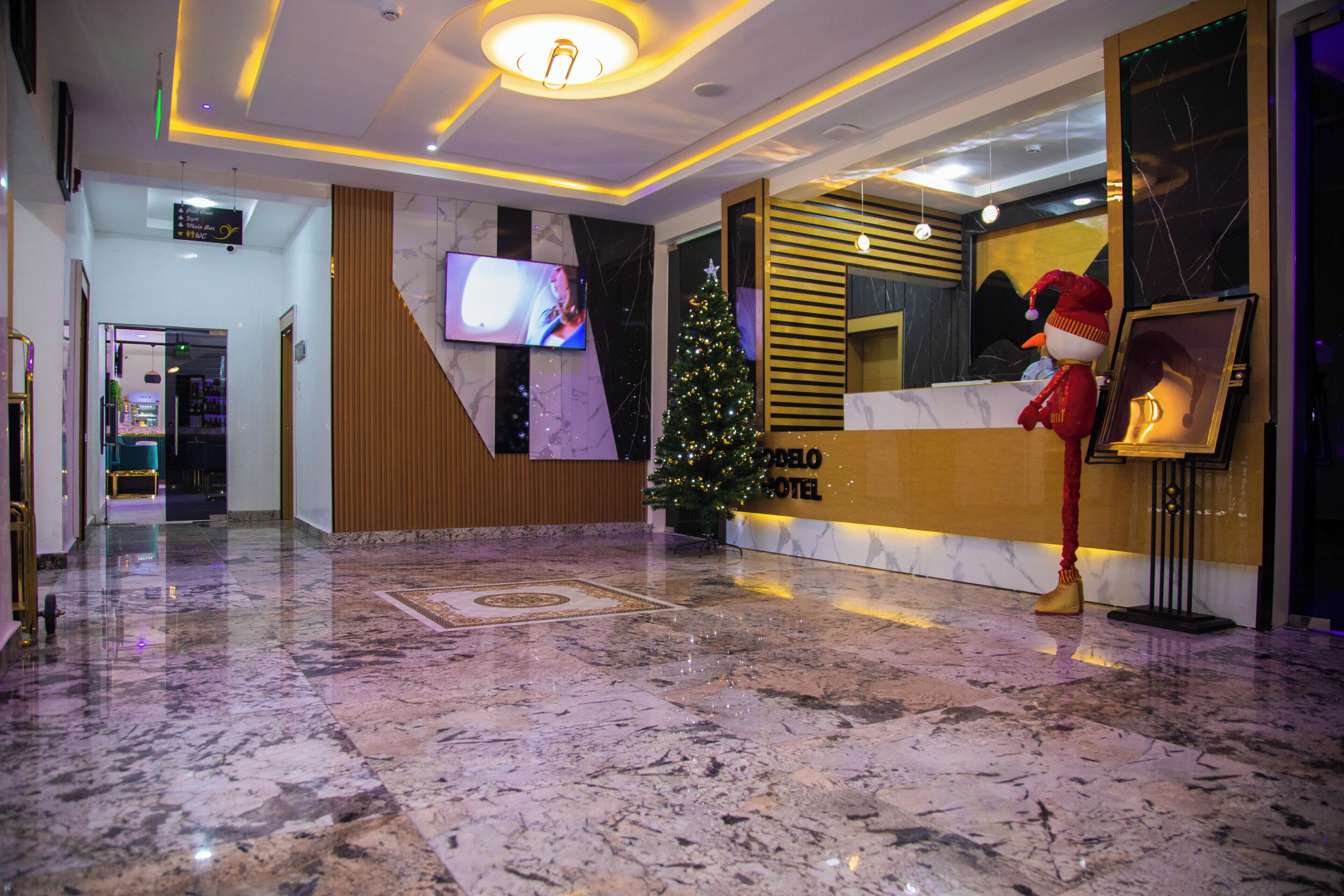 Een hotel lobby met een receptiebalie, een kerstboom en een televisiescherm.