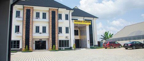 A hotel with a tiled entrance, a prominent entrance canopy, and a clear sky.