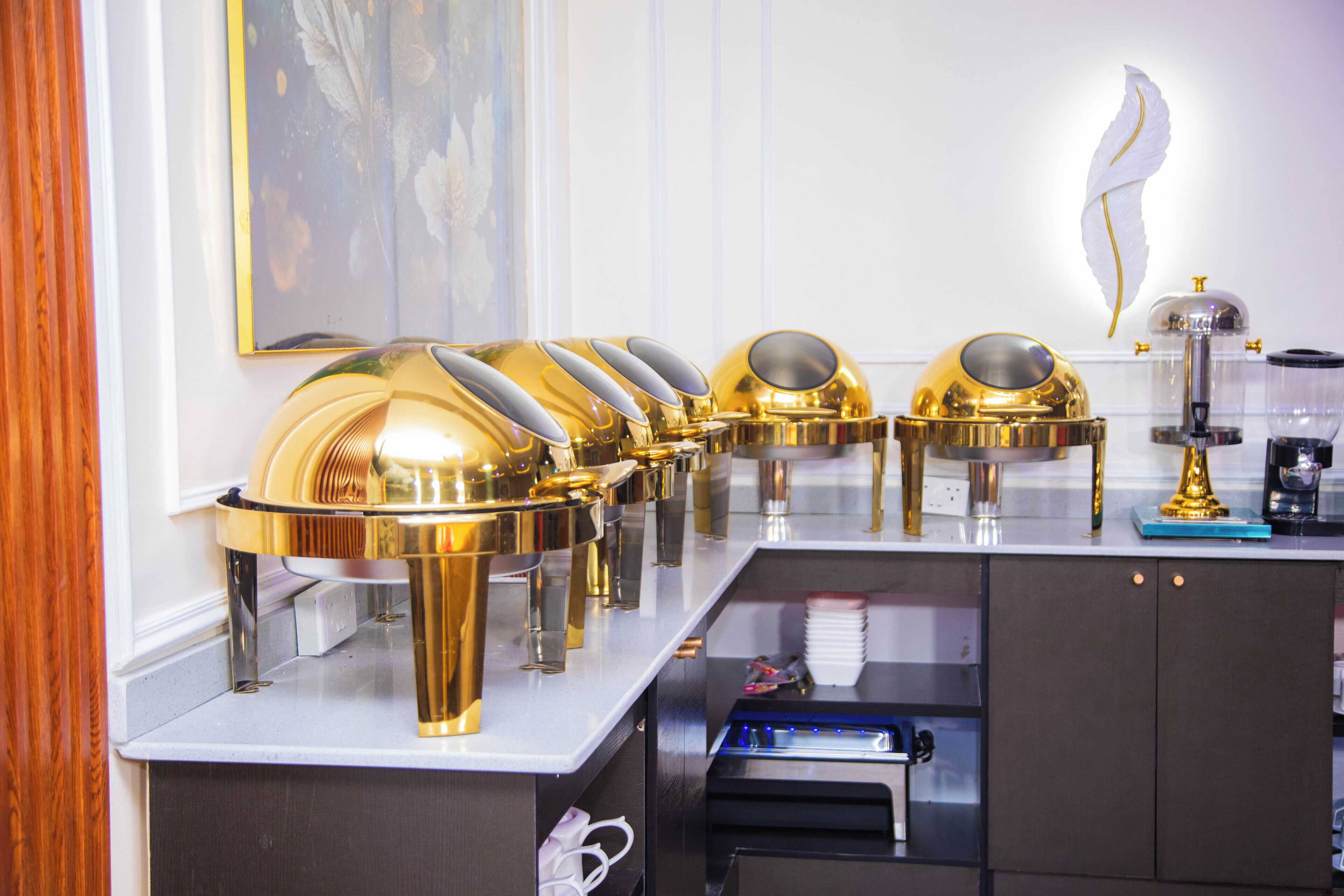 Montaje de bufé con múltiples estaciones de servicio en dorado y una máquina de café.