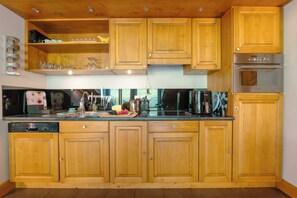 Une cuisine dotée de meubles en bois, d’un lave-vaisselle, d’un four à micro-ondes et d’une cuisinière.