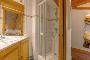 A bathroom with a shower, sink, and wooden cabinets. - V Loriaz 44: Beside Ski Lift; Pool, Sauna & Gym, Vallorcine (Argentiere), France (Vallorcine (Argentiere))