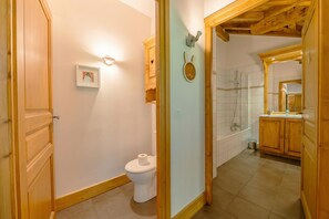 A bathroom with a toilet, a framed picture on the wall, and a shower area with a wooden ceiling. - V Loriaz 44: Beside Ski Lift; Pool, Sauna & Gym, Vallorcine (Argentiere), France (Vallorcine (Argentiere))