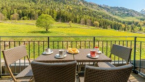 A balcony with wicker furniture, a table with a plate of croissants, and a scenic mountain view. - V Loriaz 44: Beside Ski Lift; Pool, Sauna & Gym, Vallorcine (Argentiere), France (Vallorcine (Argentiere))