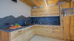A kitchen with wooden cabinets, a marble backsplash, and a built-in oven. - Casa Fiorita, Livigno, Italy (Livigno)