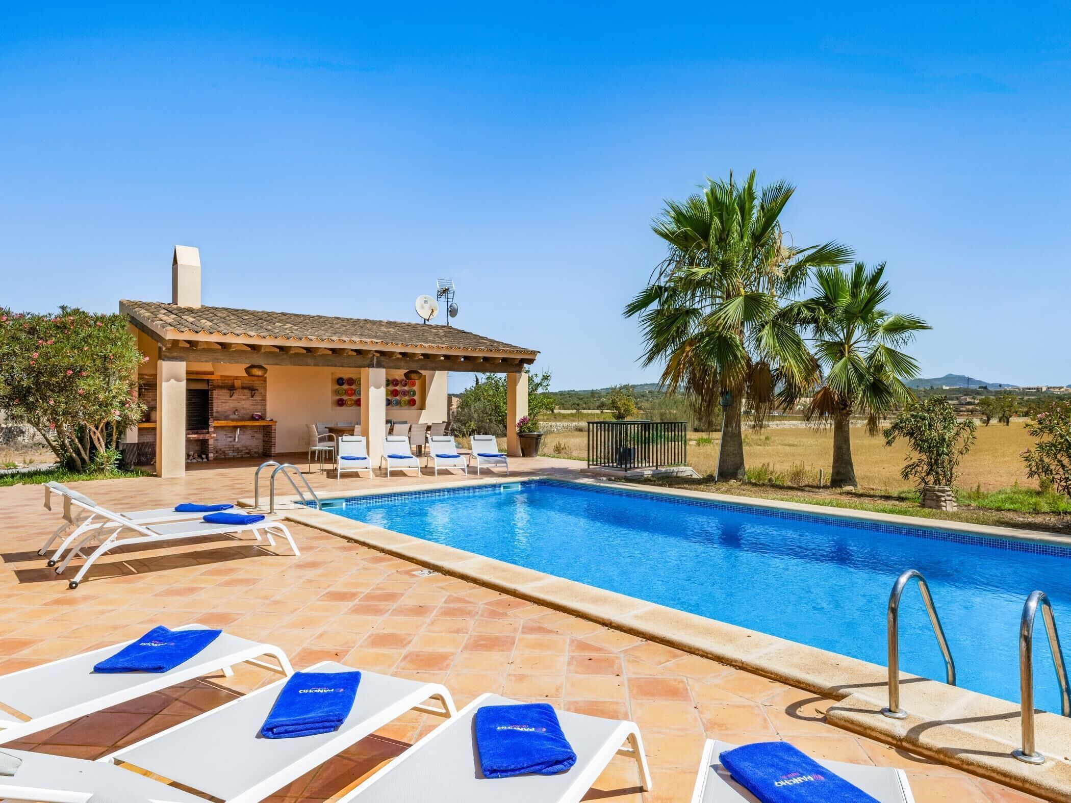 Zona de piscina con sillones de descanso y zona de barbacoa.