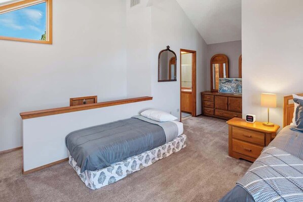 A bedroom with a single bed, a nightstand, a dresser, and a mirror.