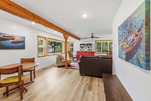 Un vaste espace de vie comprenant une table à manger en bois, un canapé et un grand tableau accroché au mur.