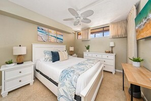 A bedroom with a bed, nightstands, a desk, a ceiling fan, and artwork on the walls. - Perfect Maui Getaway Condo w Ocean Views-Kahana Villa F405 (Lahaina)