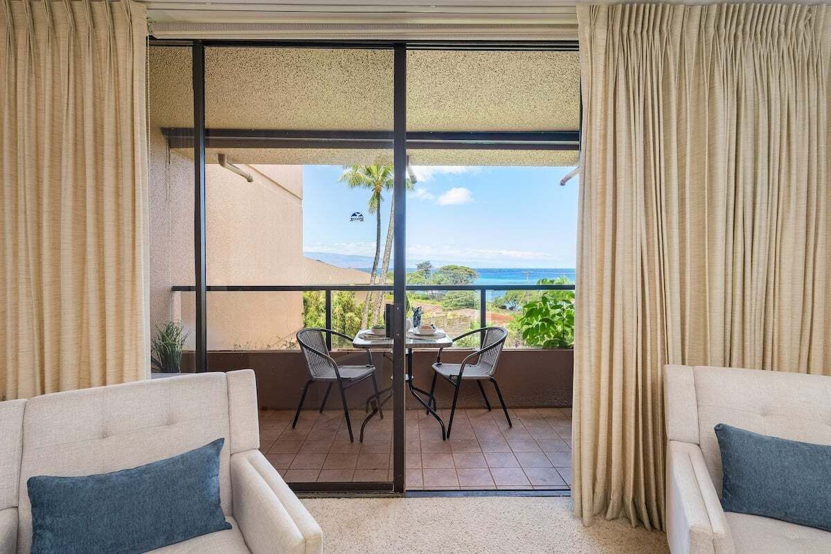 Ein Balkon mit Blick auf das Meer, zwei Stühle und ein Tisch.