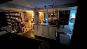 A spacious living area with a central island, a kitchen area with a built-in fridge, and a dining area with a table and chairs. - Private backyard, fire pit, bbq, beach, boats and entertainment…fun! (Lake Geneva)