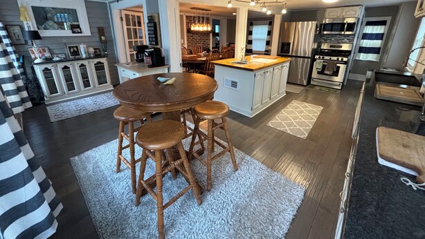 A modern kitchen with a central island, wooden bar stools, and a dining table. - Private backyard, fire pit, bbq, beach, boats and entertainment…fun! (Lake Geneva)