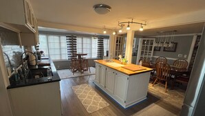 A spacious kitchen with a central island, wooden flooring, and a dining area with chairs and a table. - Private backyard, fire pit, bbq, beach, boats and entertainment…fun! (Lake Geneva)