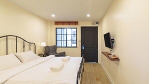 Ein Hotelzimmer mit einem großen Bett, einem Sessel, einem Fernseher und einem Fenster.