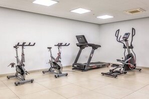 A fitness room with four exercise bikes and a treadmill.