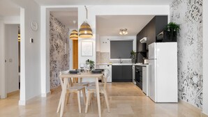 Une cuisine moderne avec un coin repas, comprenant un réfrigérateur blanc, des armoires noires et un crédence décorée.