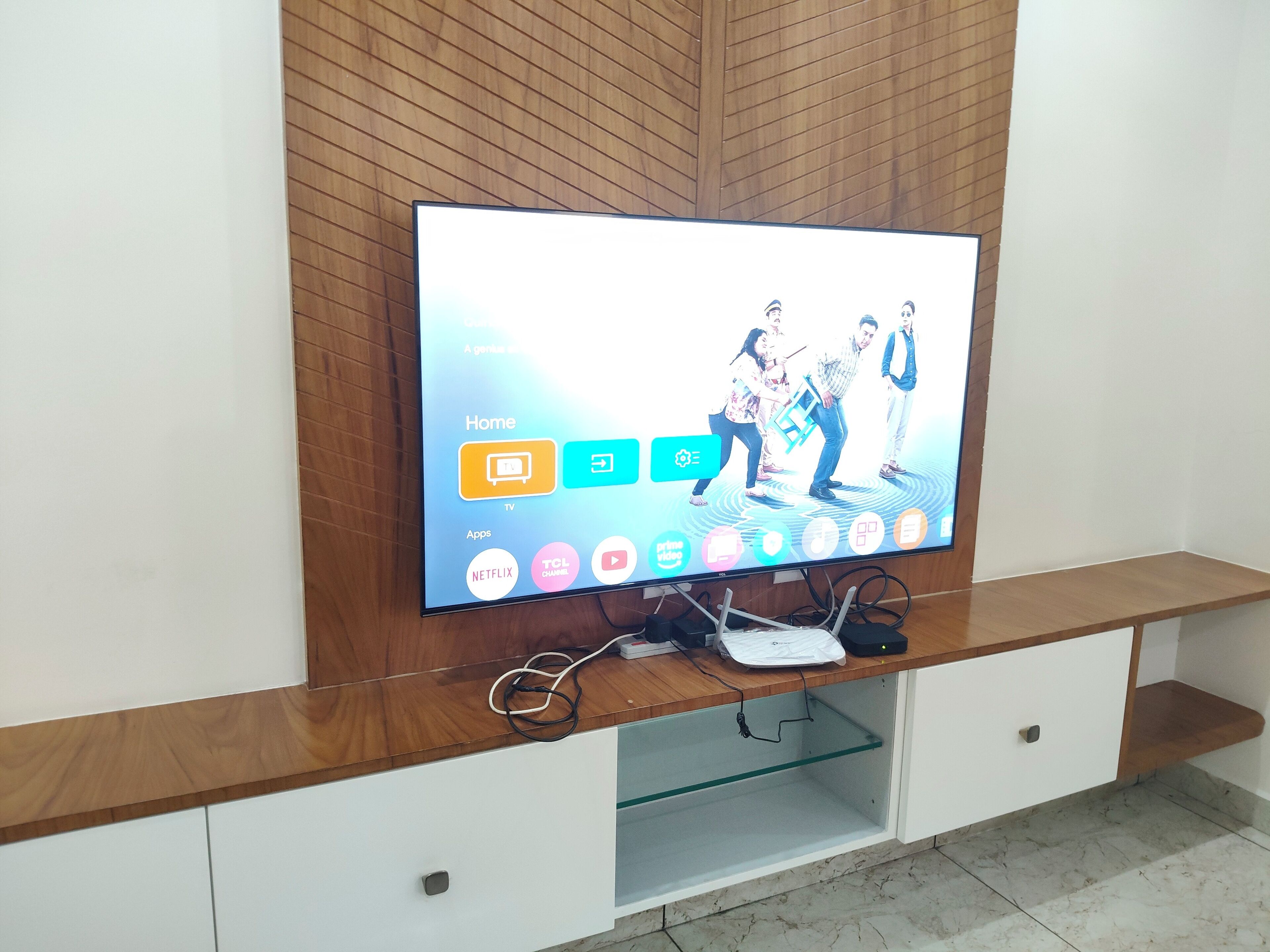 A flat-screen TV mounted on a wooden wall with a wooden shelf below.
