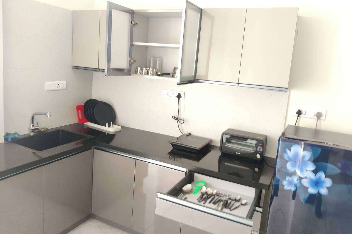 A modern kitchen with a built-in oven, a sink, and a countertop with a toaster and a kettle.