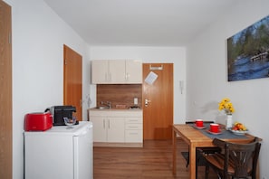 A compact kitchen with a refrigerator, a toaster, and a sink. There is a dining table with chairs and a painting on the wall. - Holiday Apartment 'Eschach' with Shared Garden, Balcony and Wi-Fi (Leutkirch im Allgäu)
