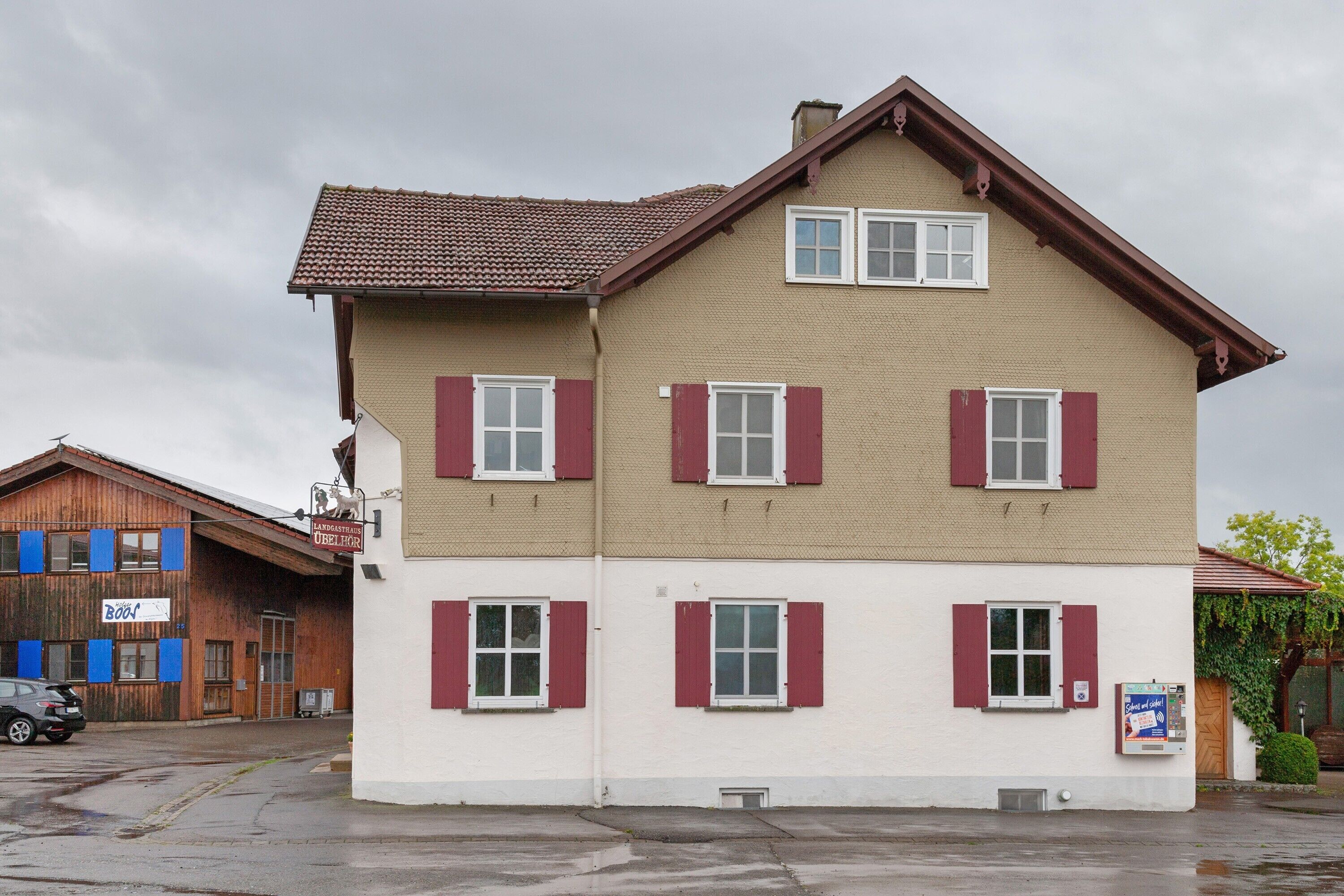 En toetages bygning med røde skodder, et tegltag og et skilt, der angiver, at det er et hotel.